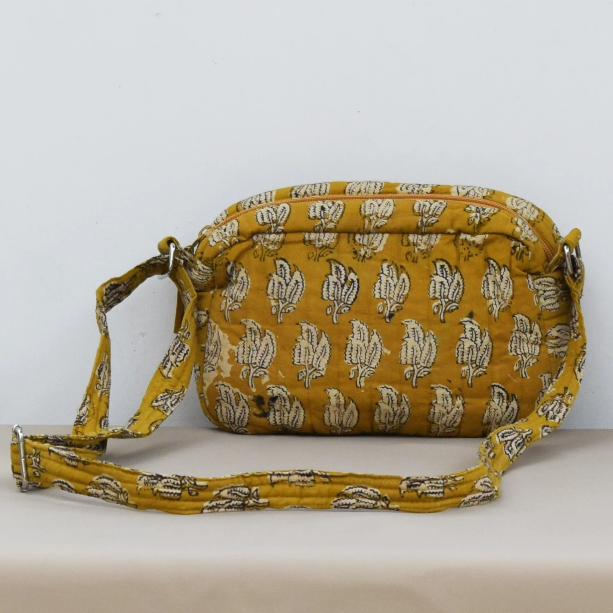 Handmade mustard yellow quilted sling bag with white leaf block print and adjustable strap
